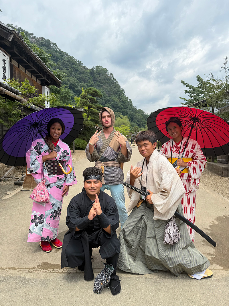 Students posing in traditional Japanese clothing with colorful umbrellas.
