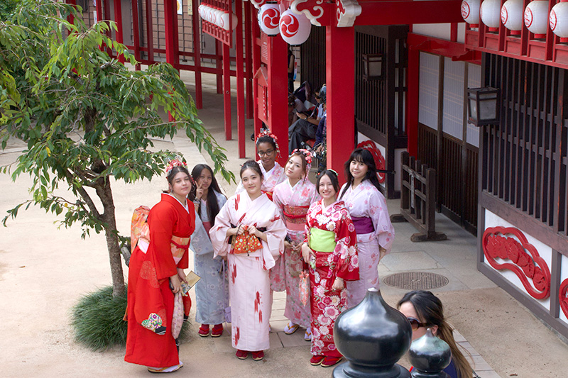A group of students wearing colorful kimonos at a traditional Japanese venue.